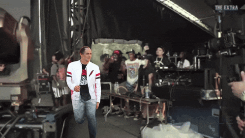 a man walking on a stage with the extra written on the bottom right