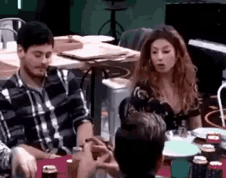 a group of people are sitting at a table drinking beer and talking .