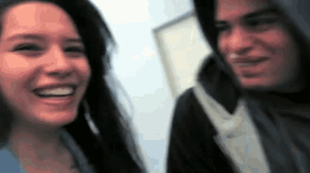 a woman is smiling next to a man in a hoodie