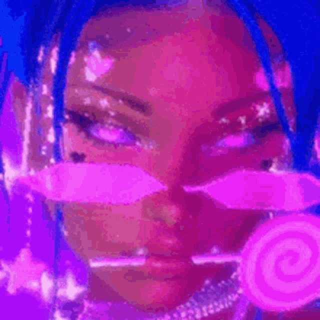 a woman with blue hair and pink makeup is holding a pink lollipop in her hand .