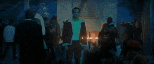 a man in a white robe is standing in front of a fireplace with a group of people .