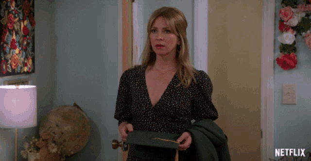 a woman in a black dress is holding a green graduation cap with a gold tassel and a netflix logo in the corner