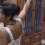 a woman in a white dress is standing in front of a door with her arm raised .