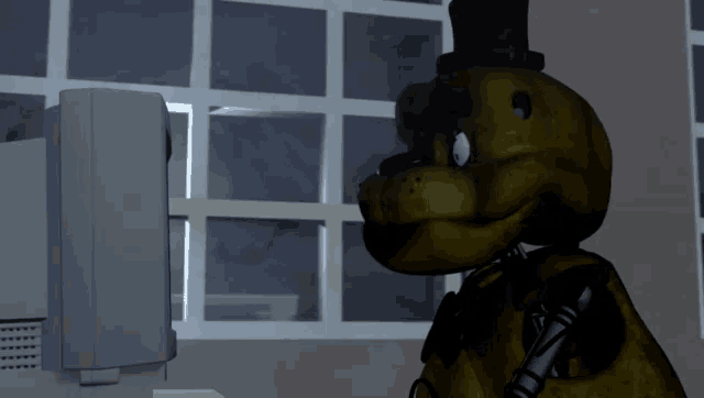 a yellow teddy bear is looking at a computer screen