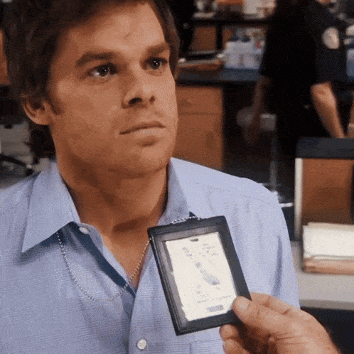 a man in a blue shirt is holding a badge that says m.j. smith