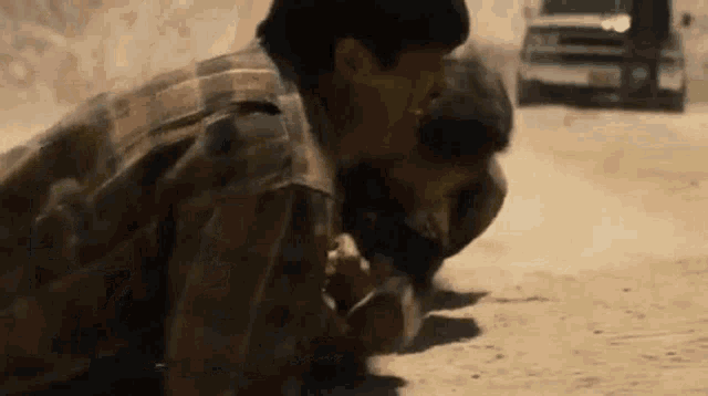 a group of soldiers are kneeling down in the dirt in front of a car .