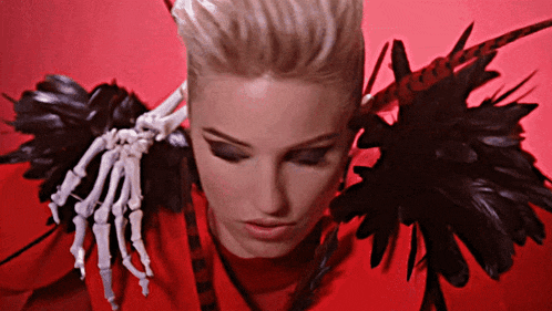 a woman with a skeleton hand on her shoulder looks down
