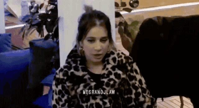 a woman in a leopard print jacket is sitting in a room with a blue chair .