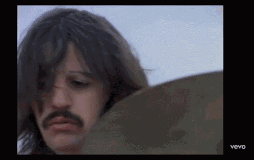 a man with a mustache is playing a drum in a video that says vevo at the bottom