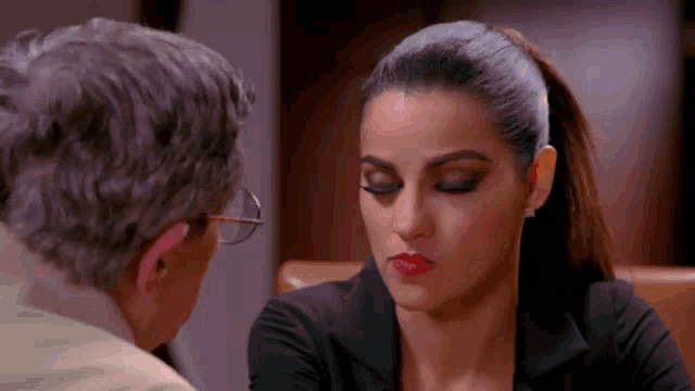 a man and a woman are looking at each other . the woman is wearing red lipstick .