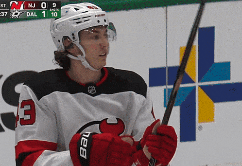 a hockey player with the number 3 on his jersey holds a hockey stick