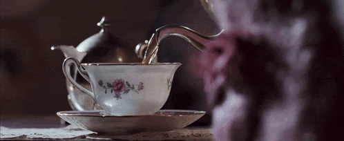 tea is being poured into a cup with a floral design