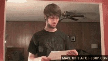a man is holding a piece of paper in front of a mirror in a room .