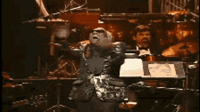 a man in a leather jacket is kneeling down on a stage