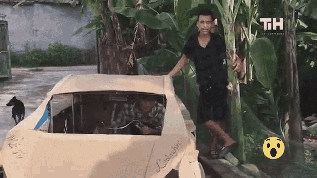 a man is standing next to a cardboard lamborghini .