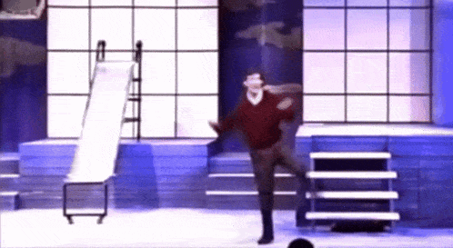 a man in a red sweater is dancing in front of a slide