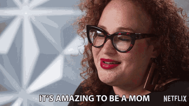a woman wearing glasses and red lipstick says " it 's amazing to be a mom "