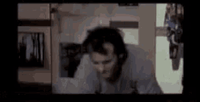 a man wearing headphones is standing in a dark room in a movie .