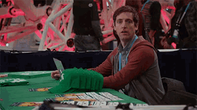 a man is sitting at a table with playing cards on it and looking at something .