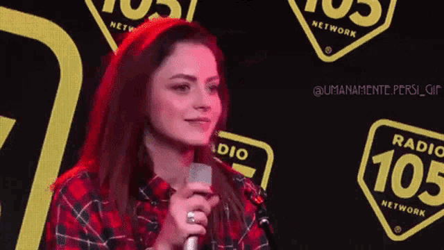 a woman singing into a microphone in front of a sign that says radio 105 network