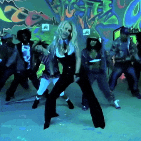 a group of people are dancing in front of a wall with graffiti that says ' a ' on it