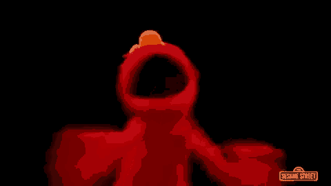 elmo from sesame street is dancing in the dark with a black background .