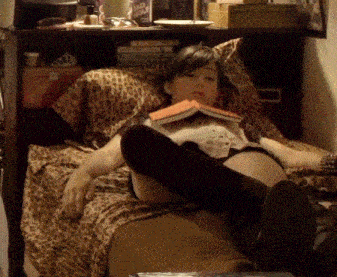 a woman laying on a bed reading a book with a leopard print comforter