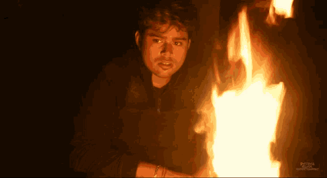 a man is standing in front of a fire with a picture of a man in front of it