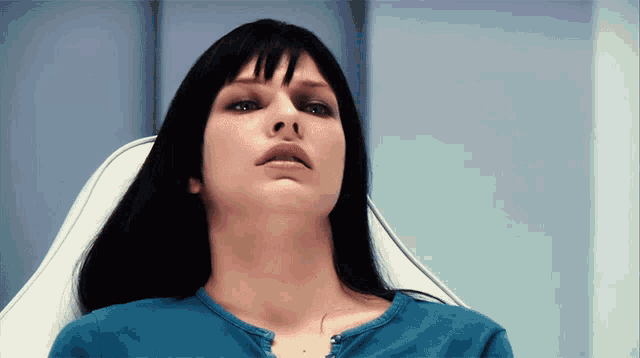 a woman with long black hair is sitting in a white chair
