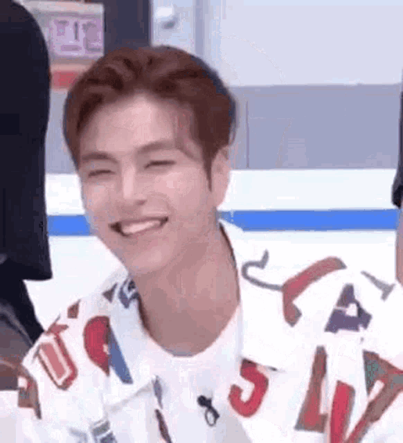 a young man wearing a colorful shirt is smiling and looking at the camera .