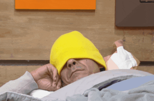 a man wearing a yellow hat is laying down