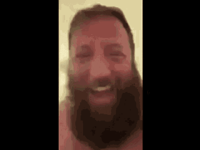 a shirtless man with a beard is laughing in a bathroom .