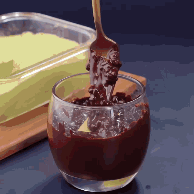 a spoonful of chocolate is being poured into a small glass