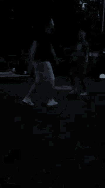 a man and a woman are dancing in the dark on a lush green field .