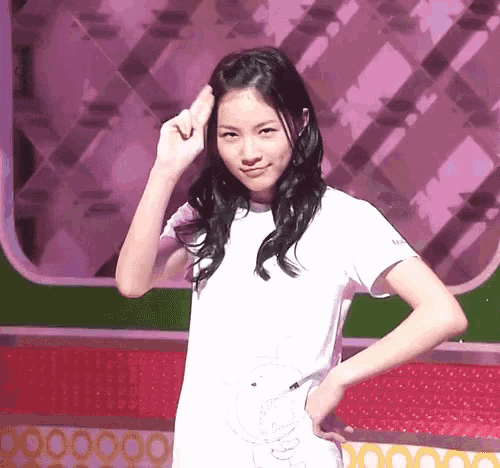 a young woman in a white t-shirt is making a peace sign with her hand .