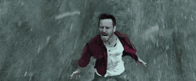 a man is screaming in the rain while standing on the ground .
