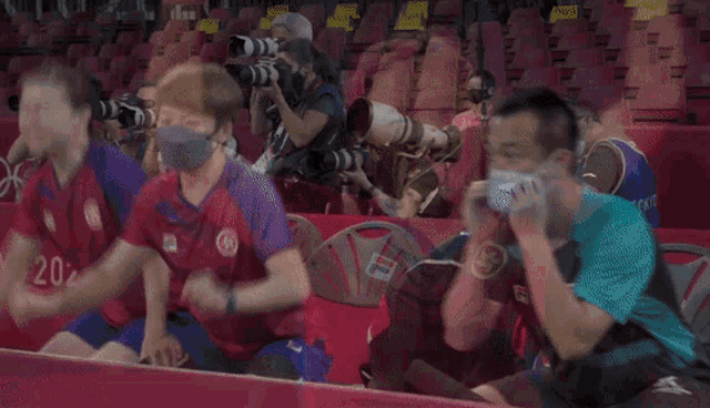 a group of people wearing face masks are watching a ping pong match .