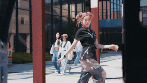 a woman with pink hair is walking down a street with other people