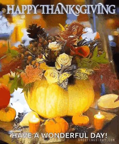 a pumpkin filled with flowers and candles is on a table with a happy thanksgiving message .