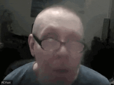 a man wearing glasses and a blue shirt is on a video call with the name pc foot at the bottom