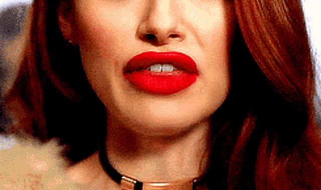a close up of a woman 's mouth with red lipstick and a choker .