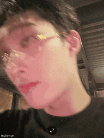 a blurry picture of a man wearing glasses and a black shirt with an arrow pointing to the left