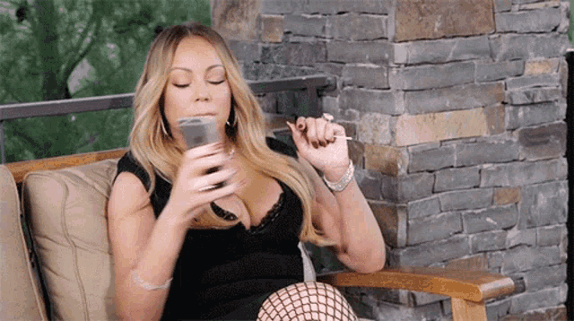 a woman is sitting in a chair smoking a cigarette and drinking a glass of wine .