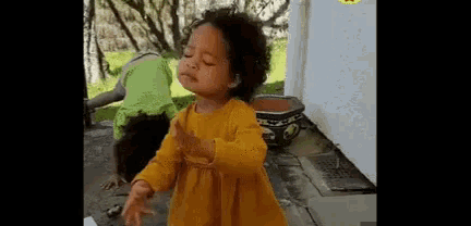 a little girl in a yellow dress is dancing with a man in a green shirt .