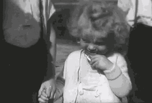 a black and white photo of a little girl holding a toothbrush .