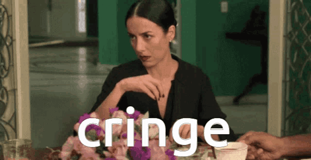 a woman is sitting at a table with flowers and the word cringe is visible