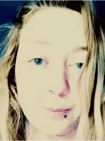 a close up of a woman 's face with blue eyes and a piercing in her lip