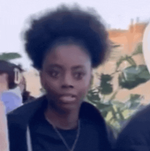 a woman with an afro is making a funny face while standing in front of a crowd of people .