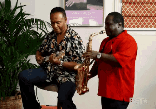 a man in a red shirt plays a saxophone while another man plays guitar