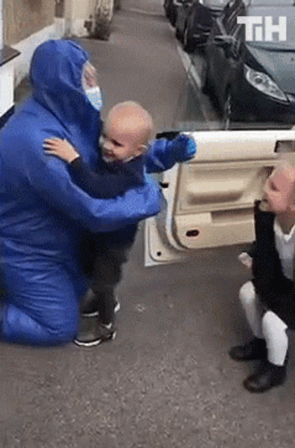 a man in a blue protective suit is hugging a little boy